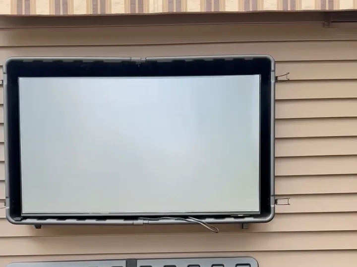 Outdoor TV mounted on house siding with anti-glare film on the screen
