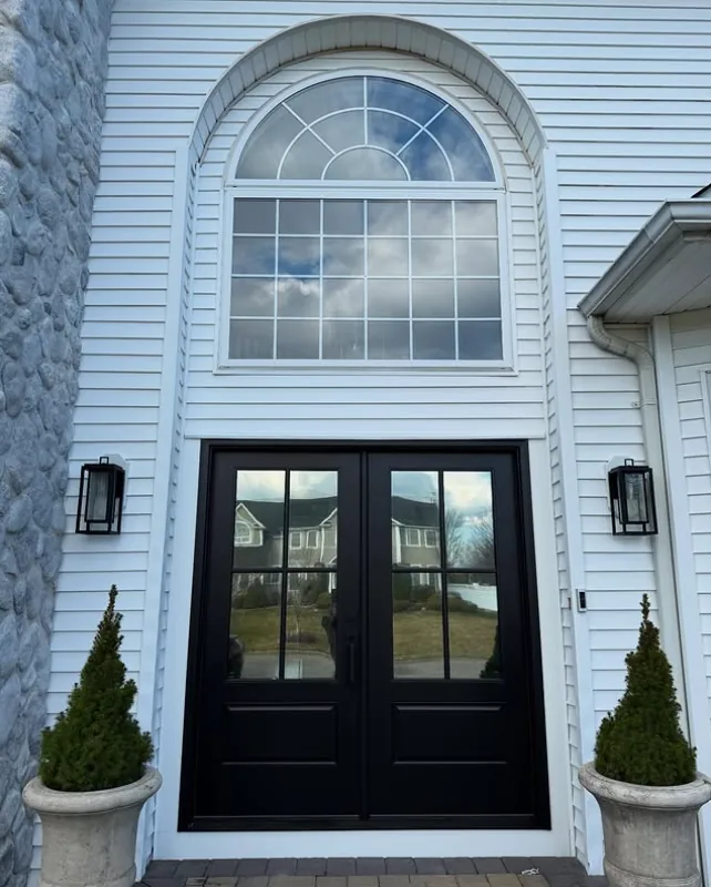 Front entry double doors with dark privacy film, reflecting the yard from outside during the day