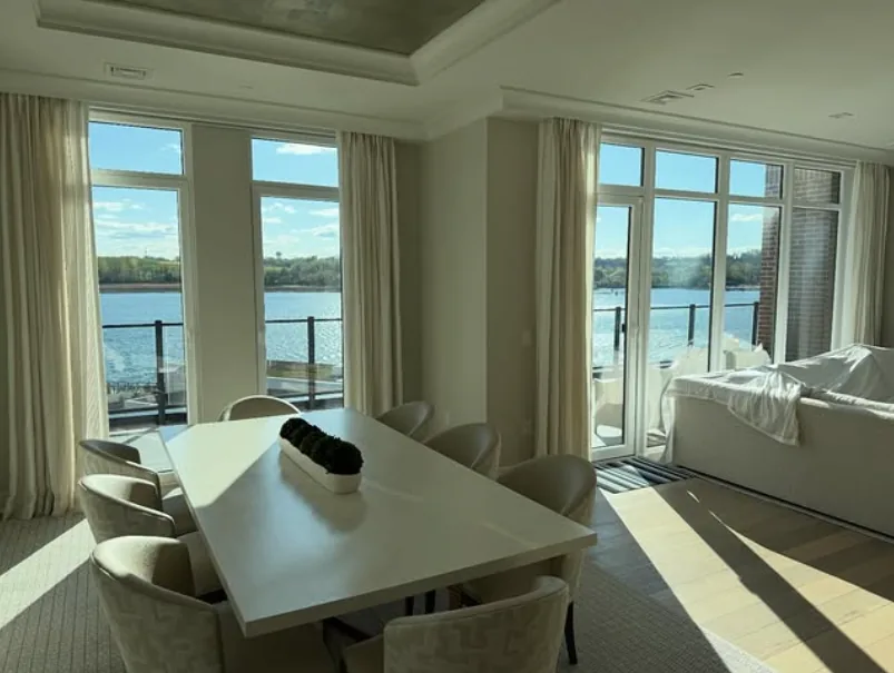 Bright waterfront dining room with 70% clear ceramic film on floor-to-ceiling windows overlooking the water